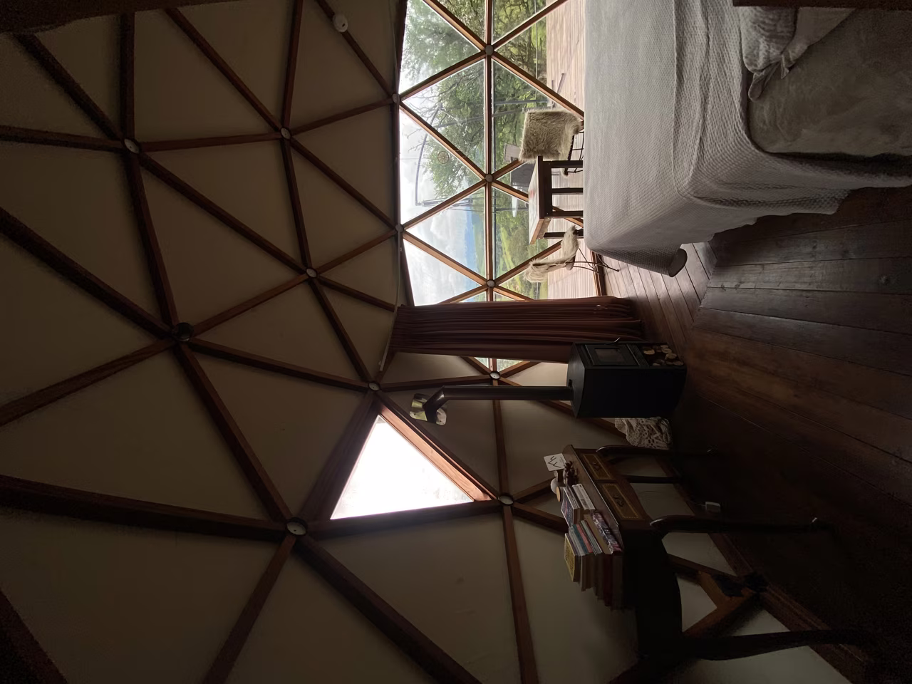 Interior do Domo Kali com aquecedor a lenha, cama e parede de vidro para a vista