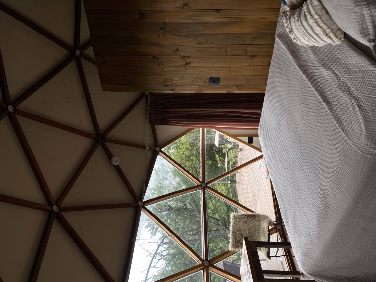 Cama do Domo Kali de frente para a serra, pela parede de vidro geodésica